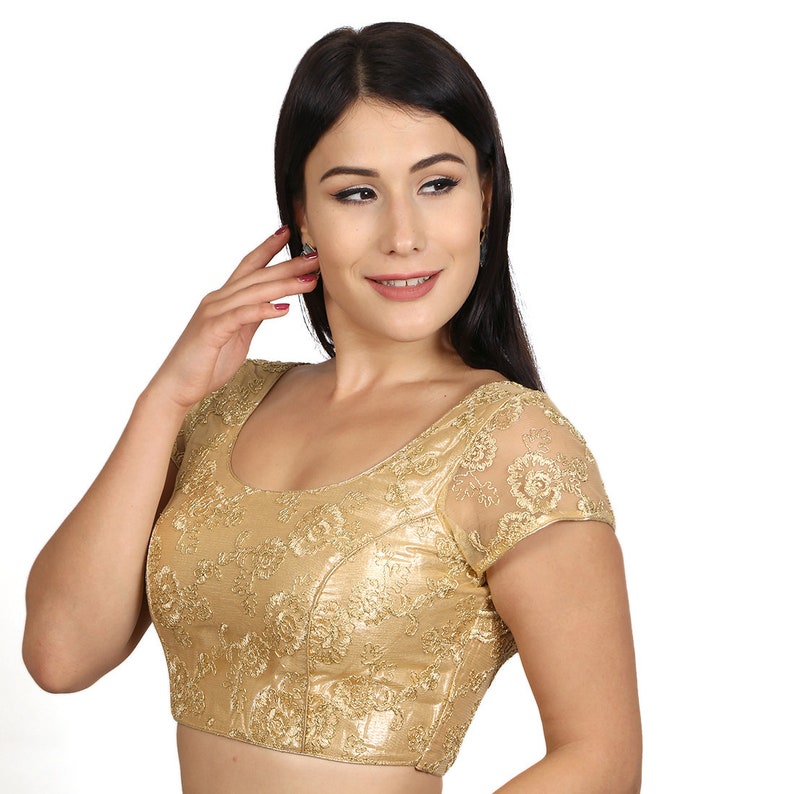 May include: A gold embroidered blouse with short sleeves and a scoop neckline. The blouse is made of a sheer fabric with a floral pattern.