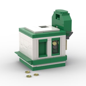 May include: A small, green and white model building with a window showing coins. The model has a rectangular base, green roof and trim. Three gold-coloured coins are scattered in front of the building.