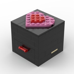 Peut inclure: Une boîte LEGO noire avec un tiroir et un couvercle en forme de cœur rose avec un cœur rouge au centre.