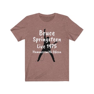 May include: A heather gray t-shirt with a black silhouette of a person playing guitar. The text "Bruce Springsteen Live 1975 Hammersmith Odeon" is printed in white on the shirt.
