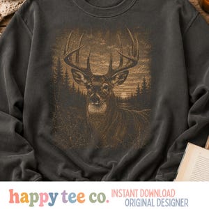 Puede incluir: Una sudadera gris carbón de cuello redondo con un estampado gráfico detallado en tonos sepia de un gran ciervo con cornamenta en un paisaje forestal al atardecer, que incluye siluetas de pinos y un sol en el horizonte.