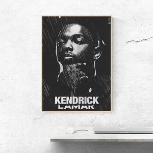 Könnte beinhalten: Schwarz-Weiß-Porträt von Kendrick Lamar in einem goldgerahmten Druck. Das Bild zeigt eine stilisierte Illustration des Künstlers mit dem Namen "Kendrick Lamar" in fetter weißer Schrift am unteren Rand. Das Kunstwerk wird an einer weißen Wand gezeigt.