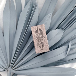 May include: A wooden stamp with a floral design. The stamp is rectangular and has a light brown color. The design features a floral motif with a delicate, intricate pattern.