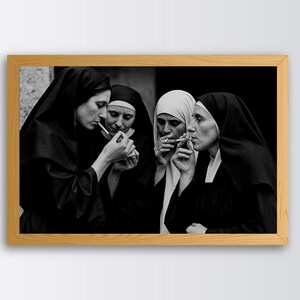 May include: Black and white framed photograph showing four nuns smoking cigarettes. The nuns are dressed in traditional habits, with black veils and white collars. The image is a medium shot, with the nuns in the centre of the frame.