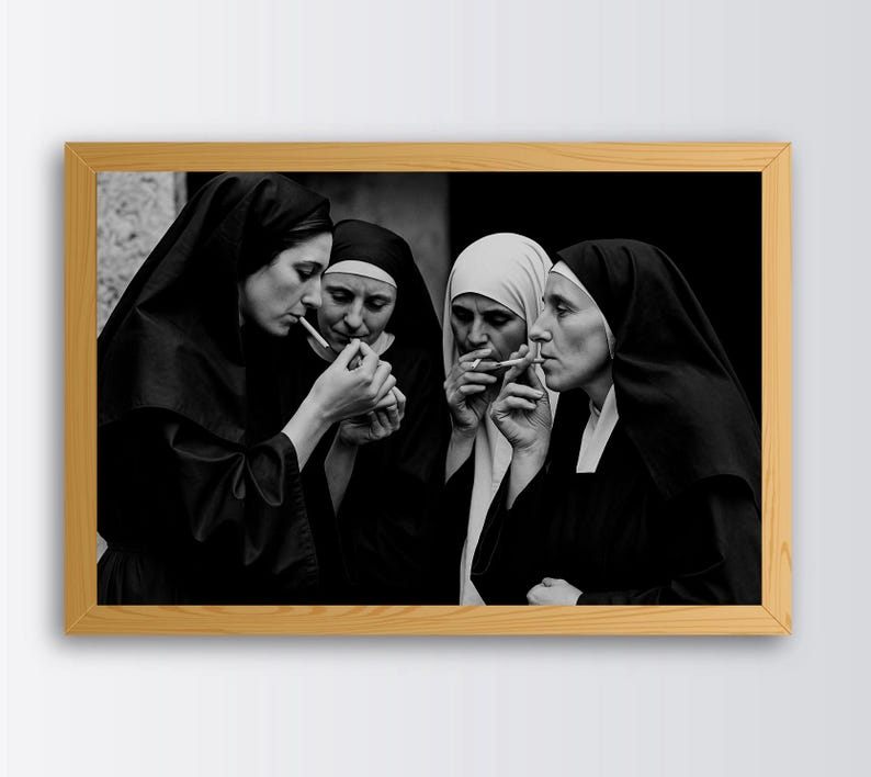May include: Black and white framed photograph showing four nuns smoking cigarettes. The nuns are dressed in traditional habits, with black veils and white collars. The image is a medium shot, with the nuns in the centre of the frame.