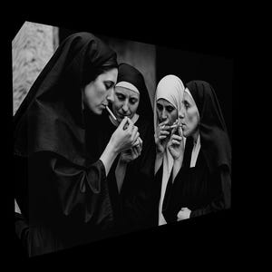 May include: A monochrome image showing four nuns in their habits, smoking cigarettes. One nun is using a lighter to light a cigarette for another. The image uses light and shadow to create a striking contrast.