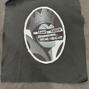 May include: Black fabric patch with a grayscale illustration of a queen wearing a crown. The text "GOD Save THE QUEEN" and "Fair Rasi of Them aLL" is printed on the patch.