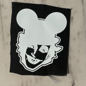 May include: White iron-on patch with a black and white image of a cartoon character with Mickey Mouse ears. The character has a wide smile and is wearing a mask.
