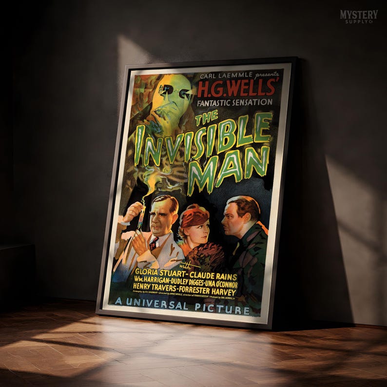 May include: A framed movie poster for The Invisible Man, featuring a large, ghostly, green-tinted face at the top and three people below. The text reads Carl Laemmle presents H.G. Wells' Fantastic Sensation The Invisible Man, A Universal Picture.