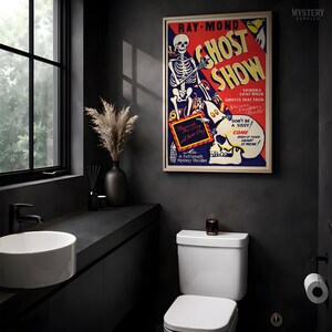 May include: A rectangular framed poster titled Ray-Mond Ghost Show featuring a skeleton illustration, red and yellow background, and text including Spooks That Walk, Ghosts That Talk, Shivers, Shudders, Thrills, and Don't Be A Sissy, Come Even If Your Heart Is Weak.