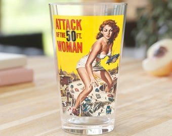 Könnte beinhalten: Ein klares Glas mit gelbem Hintergrund und einem Design eines Vintage-Filmplakats. Das Plakat zeigt eine Frau in einem weißen Badeanzug, die auf einer Autobahn steht, auf der Autos vorbeifahren. Der Text auf dem Plakat lautet "Attack of the 50 ft. Woman".