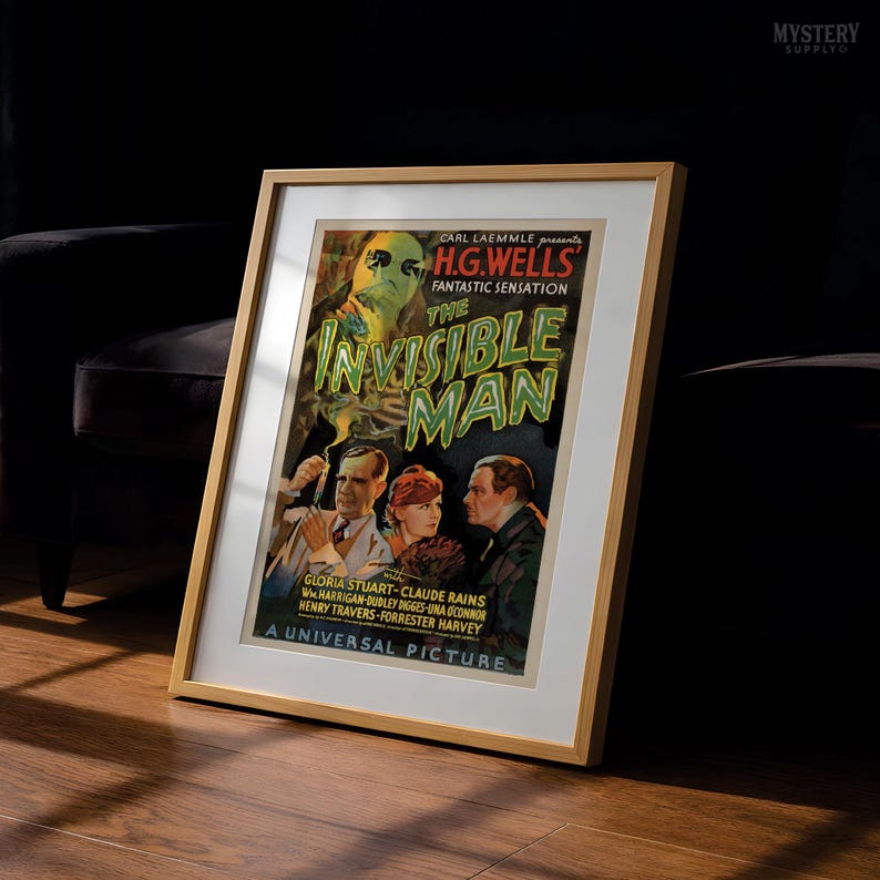 May include: A framed vintage movie poster for The Invisible Man, featuring a green-tinted figure, three actors, and bold text. The poster includes credits for Carl Laemmle, H.G. Wells, Gloria Stuart, Claude Rains, and the Universal Pictures logo.