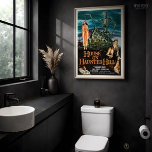 May include: A framed movie poster for House on Haunted Hill featuring a skeleton reaching toward a woman in a yellow dress, a man in a suit, and a dark mansion. The poster includes the title text and actor names in a bold, orange font.