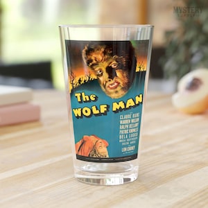 May include: A clear glass pint glass with a vintage movie poster design featuring a werewolf. The poster is for the film "The Wolf Man" and features the text "Claude Rains, Warren William, Ralph Bellamy, Patric Knowles, Bela Lugosi, Lon Chaney".