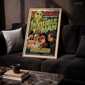 May include: A framed movie poster for The Invisible Man, featuring a green-tinted ghostly figure above three people. The text reads Carl Laemmle presents H.G. Wells Fantastic Sensation The Invisible Man, starring Gloria Stuart and Claude Rains.