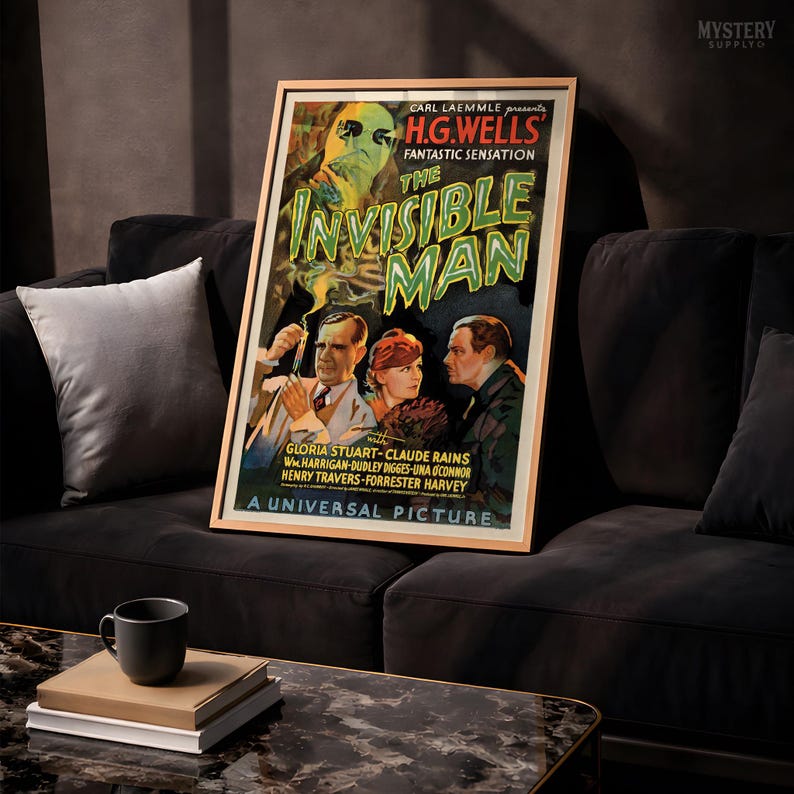 May include: A framed movie poster for The Invisible Man, featuring a green-tinted ghostly figure above three people. The text reads Carl Laemmle presents H.G. Wells Fantastic Sensation The Invisible Man, starring Gloria Stuart and Claude Rains.
