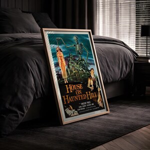 May include: A framed movie poster for House on Haunted Hill featuring a skeleton reaching toward a woman in a yellow dress, a man holding a candle, and a dark mansion. The text reads House on Haunted Hill, Vincent Price, Carol Ohmart, Richard Long.