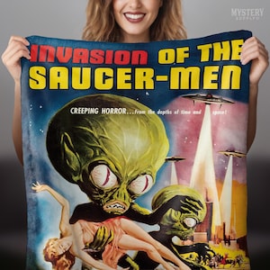 May include: A vintage movie poster for the film "Invasion of the Saucer-Men". The poster features a green alien with large eyes holding a woman in its arms. The text "CREEPING HORROR... from the depths of time and space!" is printed at the top of the poster.