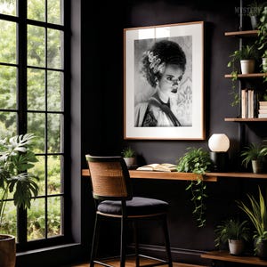 May include: A framed black and white portrait of a person with voluminous hair and a distinct white streak, displayed on a dark wall above a wooden desk. The desk features a black chair with a cane back, a small lamp, and several potted plants.
