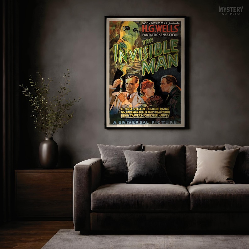 May include: A framed movie poster for the 1933 film The Invisible Man. The poster features a large, ghostly, translucent head at the top, with three people below in suits and dresses. The text reads Carl Laemmle presents H.G. Wells Fantastic Sensation The Invisible Man with Gloria Stuart, Claude Rains, William Harrigan, Dudley Digges, Una O'Connor, Henry Travers, Forrester Harvey, A Universal Picture.