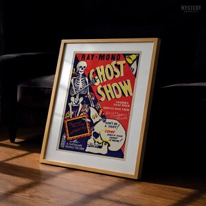 May include: A framed vintage-style poster titled Ghost Show by Ray-Mond, featuring a skeleton, a ghost, and a skull against a red and blue background. The text reads Spooks That Walk, Ghosts That Talk, Don't Be A Sissy, and Come Even If Your Heart Is Weak.