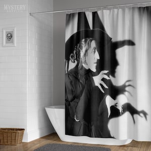 May include: Black and white photograph of a woman in a witch costume with a pointed hat. She is making a gesture with her hand, and her shadow is cast on the wall behind her.