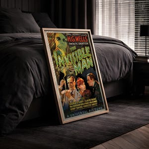 May include: A framed movie poster for The Invisible Man, featuring a green title, a central illustration of a man in a lab coat holding a test tube, a woman, and another man, with text including Carl Laemmle presents and A Universal Picture.