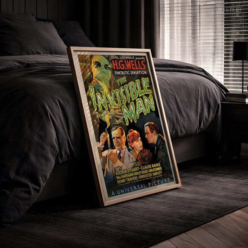 May include: A framed movie poster for The Invisible Man, featuring a green title, a central illustration of a man in a lab coat holding a test tube, a woman, and another man, with text including Carl Laemmle presents and A Universal Picture.