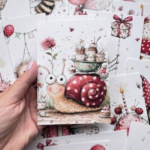 May include: A rectangular greeting card featuring a whimsical illustration of a snail with a large red and white polka-dot shell. The snail carries a stack of teacups and a bowl on its back, with a pink rose and small cupcakes nearby.