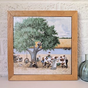 May include: A framed print depicts a picnic scene under a large tree by a river. A group of people are gathered around a table, and a tire swing hangs from a tree branch. Two decorative glass bottles in shades of blue and gray sit nearby.