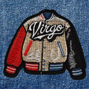 May include: Embroidered patch in the shape of a varsity jacket. The jacket is tan with red and black sleeves, and the word "Virgo" is stitched across the front in a cursive font. The patch is set against a blue denim background.