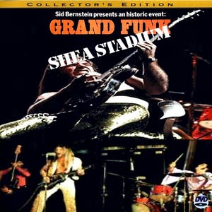 May include: DVD cover for Grand Funk's Shea Stadium concert. The image features a live performance with a guitarist in the foreground, playing a black guitar. The text "Grand Funk" and "Shea Stadium" are prominently displayed.