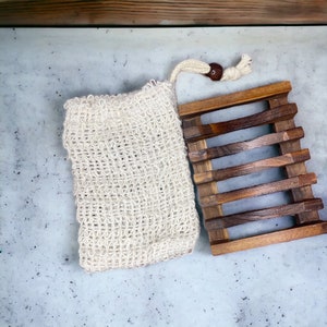 May include: A white mesh soap bag and a wooden soap dish with five slots. The soap dish is made of dark brown wood.