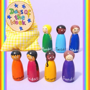 May include: Wooden peg dolls representing the days of the week. Each doll is painted a different color and has a smiling face. A wooden disc with the text "Days of the Week" is included, along with a yellow gingham bag.