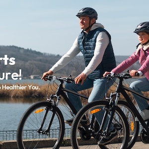 Puede incluir: Dos personas montan en bicicletas negras por un camino junto a un lago. Llevan cascos y ropa informal. La imagen incluye el texto "Wellness That Starts With Nature!" y el bot&oacute;n "Explore Now".