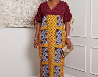 Könnte beinhalten: Ein langes, gemustertes Kleid mit V-Ausschnitt und kurzen Ärmeln. Das Kleid zeigt eine Kombination aus gelben, blauen und roten geometrischen Mustern. Ein passendes Kopftuch und eine goldene Clutch vervollständigen das Ensemble. Das Kleid ist ein stilvolles Beispiel für afrikanisch inspirierte Mode.