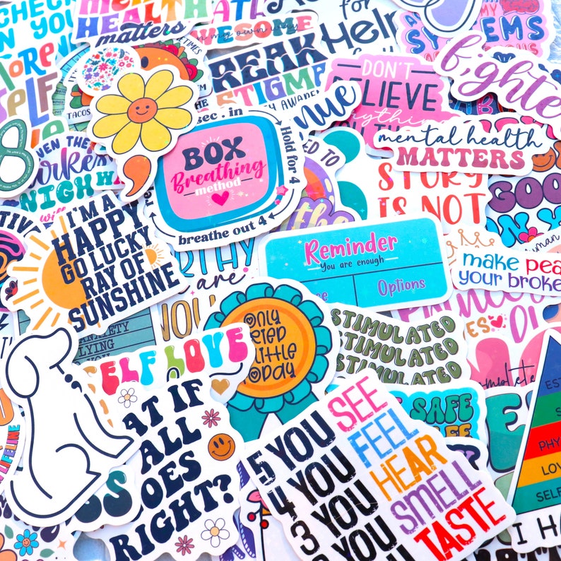 Pu&ograve; includere: Una collezione di adesivi colorati con vari messaggi positivi e design. Alcuni degli adesivi includono frasi come "Sono un raggio di sole felice e fortunato", "Amore per se stessi", "La salute mentale conta" e "Sei abbastanza".
