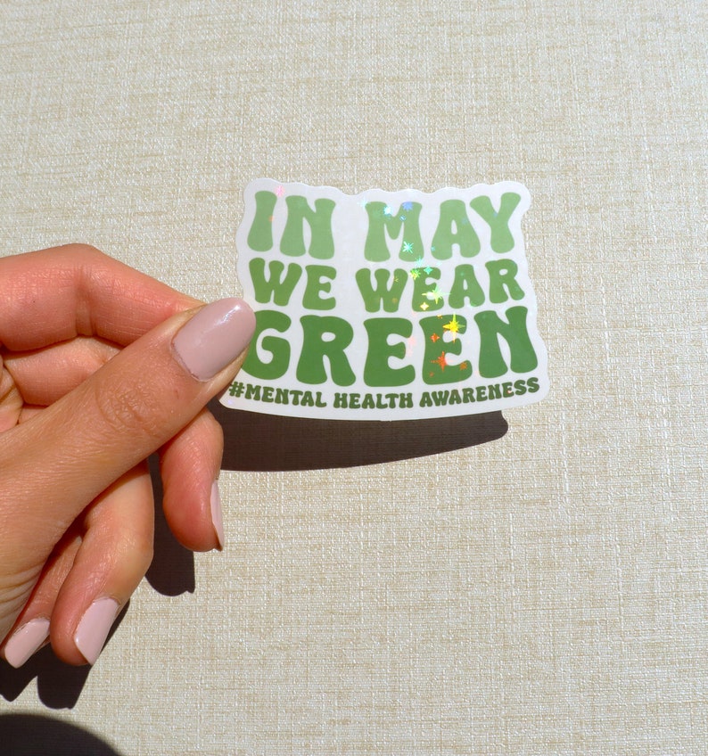 Pu&ograve; includere: Sticker verde con il testo "In May We Wear Green" e l'hashtag "#MentalHealthAwareness".