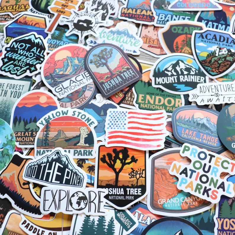 Peut inclure: Un assortiment d'autocollants color&eacute;s sur le th&egrave;me des parcs nationaux et des voyages. Les autocollants pr&eacute;sentent des illustrations de montagnes, d'arbres et du drapeau am&eacute;ricain. Le texte comprend "Joshua Tree National Park" et "Explore".
