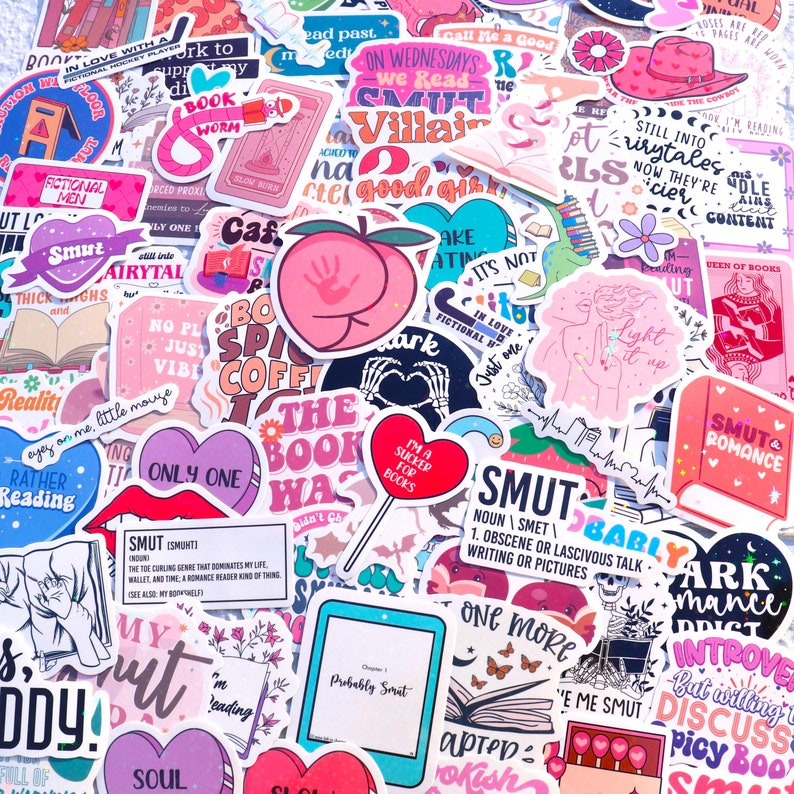 May include: A collection of colorful stickers featuring various designs related to books and reading. Some of the stickers include phrases like "The Book Was", "Smut", "Only One", "In Love With a Fictional Man", and "Light It Up".