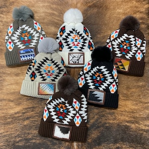 May include: Six colorful knit winter hats with pom poms. Each hat features a geometric pattern and a leather patch with a different design.