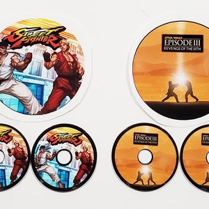 May include: Five round stickers, two with a black background and a colorful image of two characters from the video game Street Fighter, two with an orange background and a silhouette of two figures from the movie Star Wars Episode III: Revenge of the Sith, and one with a white background and a colorful image of two characters from the video game Street Fighter.