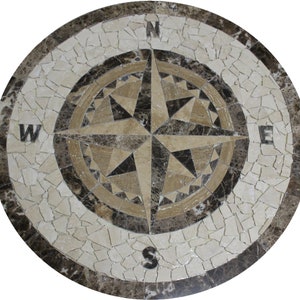 May include: A round marble mosaic floor tile with a compass rose design. The compass rose is made of beige, brown, and black marble tiles. The tile is surrounded by a border of brown marble tiles.