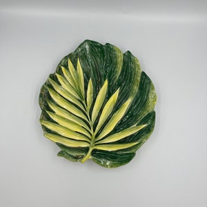 May include: A ceramic dish shaped like a green and yellow leaf. The leaf has a raised design and is perfect for serving snacks or holding jewelry.
