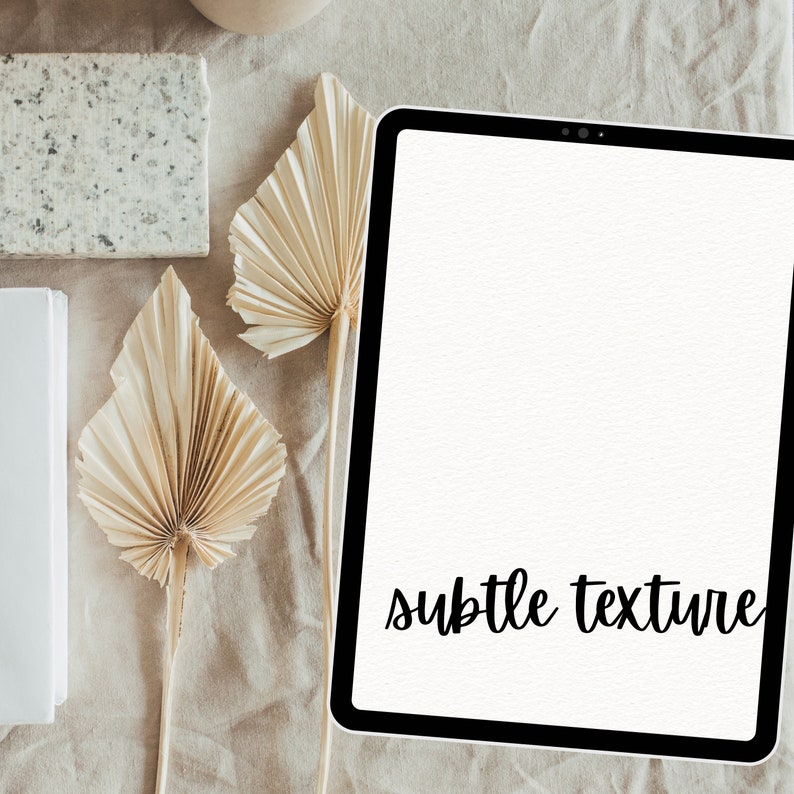 May include: A white tablet with a black border and the text "subtle texture" on the screen. The tablet is on a beige surface with dried palm leaves.