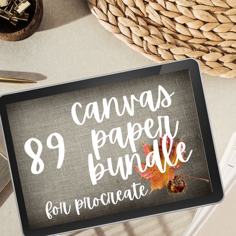 May include: A digital tablet screen displaying a graphic with the text "89 canvas paper bundle for procreate" in white text on a brown textured background. A red and orange leaf with a brown acorn is in the lower right corner of the screen.