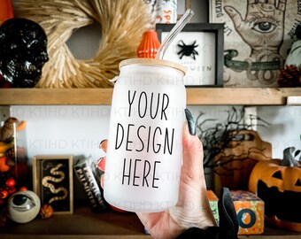 May include: A white tumbler with a black lid and a black straw. The tumbler has the text "YOUR DESIGN HERE" written on it. The tumbler is being held by a hand.