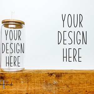 Könnte beinhalten: Ein durchsichtiger Glasbecher mit einem Holzdeckel und einem Strohhalm. Der Becher hat den Text "YOUR DESIGN HERE" aufgedruckt. Der Becher steht auf einer Holzoberfläche.