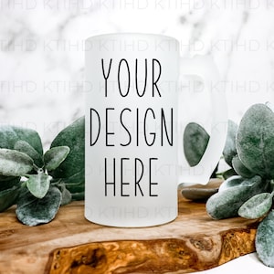 May include: A frosted glass beer mug with a black handle. The mug has the text "YOUR DESIGN HERE" printed on the front.