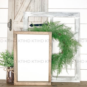 Puede incluir: Un letrero con marco de madera con un espacio en blanco, una corona verde y una pequeña planta verde en un frasco de vidrio. El letrero está apoyado contra un marco de ventana pintado de blanco y una puerta de madera pintada de blanco.